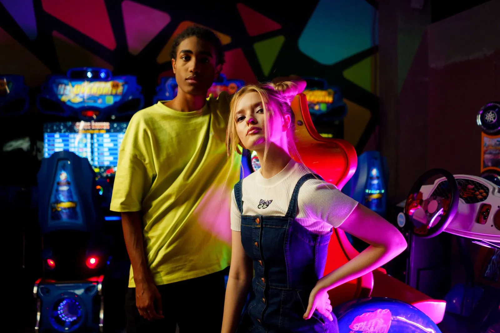 Two young adults enjoying a night at a colorful arcade center, surrounded by vibrant neon lights and arcade machines.